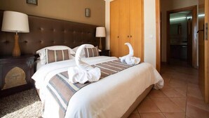 A hotel room with a large bed, two bedside lamps, a wooden wardrobe, and a carpeted floor. - Residence La Source Taghazout 5217 (Taghazout)