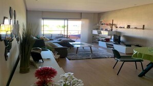 Een moderne woonkamer met een bank, salontafel en een eethoek met een tafel en stoelen.