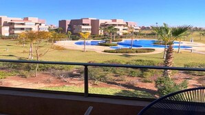 Uitzicht op een hotel met meerdere gebouwen, een zwembadgedeelte en een balkon met een stoel.
