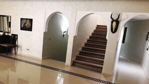 Un pasillo con piso pulido, una escalera con peldaños estampados y una calavera de ciervo montada en la pared.