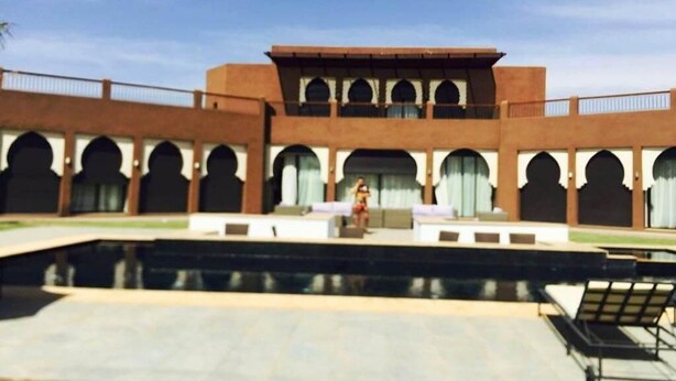 Un edificio con patio, piscina y una persona sentada en un banco.