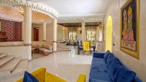 A spacious lobby with a blue sofa, yellow cushions, a dining area, and a large painting on the wall. - High standing villa with swimming pool 5231 (Marrakech)