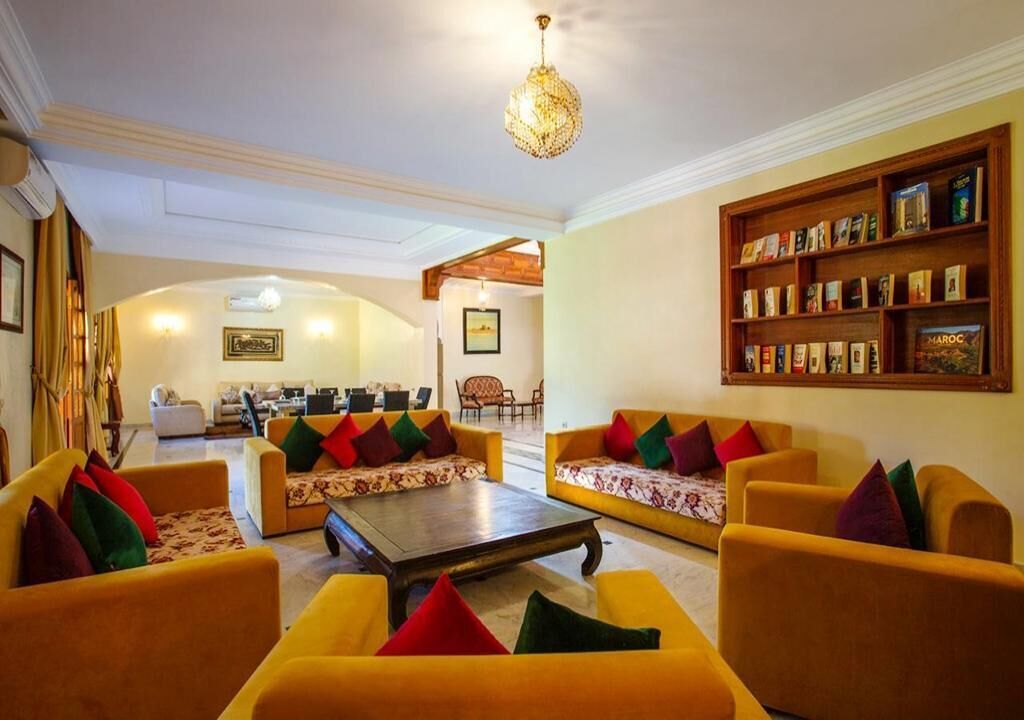 A spacious lobby with yellow sofas, a coffee table, and a bookshelf filled with books.