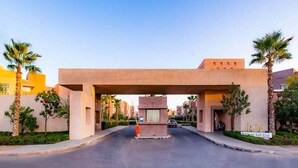 A gated entrance to a residential area with a central gate and palm trees on either side. - Splendid apartment in Prestigia Marrakech 5234 (Marrakech)