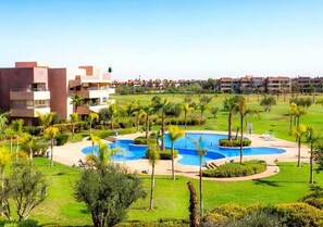 A resort with a central swimming pool, lush greenery, and modern buildings.