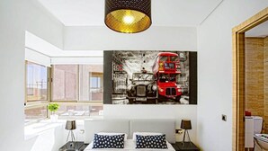 A modern bedroom with a large bed, a cityscape painting, and a view of the outside. - Splendid apartment in Prestigia Marrakech 5234 (Marrakech)