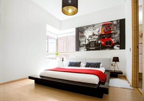 A modern bedroom with a large bed, a cityscape painting, and a skylight.
