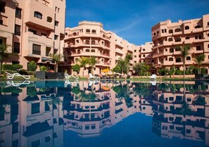 Ein Hotel mit mehreren Balkonen, einem Schwimmbad und Palmen.