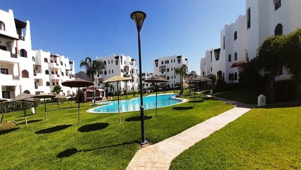 Un complexe hôtelier doté d’une piscine, de pelouses bien entretenues et d’immeubles blancs avec des balcons.