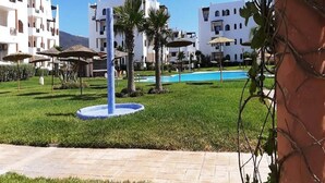 Un complexe hôtelier doté d’une piscine, de palmiers et de bâtiments blancs avec des balcons.