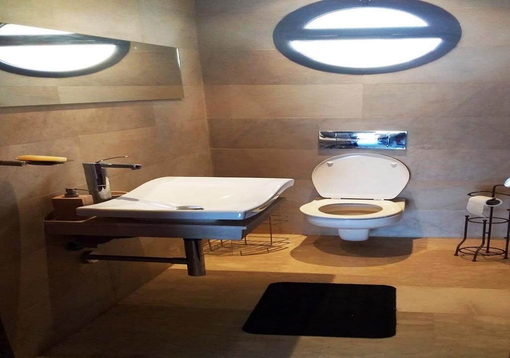 A modern bathroom with a white sink, a toilet, and a mirror.