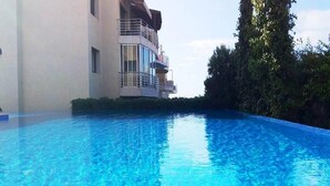 Una piscina junto a un edificio con balcón.