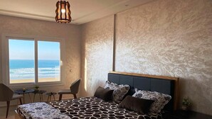 Une chambre avec un grand lit, une vue sur l’océan, un bureau et une chaise.
