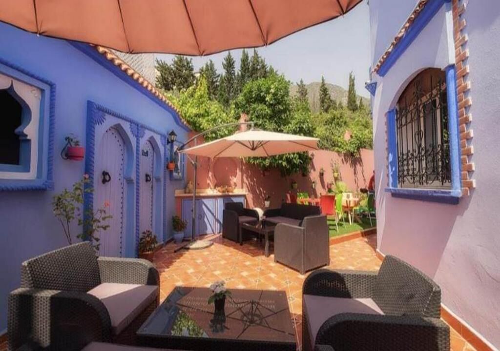 Eine Terrasse mit Gartenmöbeln, einem Tisch und einem großen Sonnenschirm.