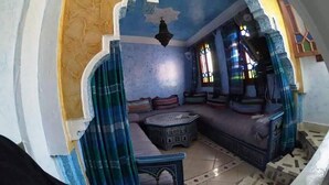 A room with a blue and yellow color scheme, featuring a seating area with cushions and a patterned coffee table. - Duplex in Chefchaouen 5264 (Chefchaouen)