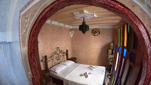 A room with a bed, a chandelier, and a wall with colorful stained glass windows. - Duplex in Chefchaouen 5264 (Chefchaouen)