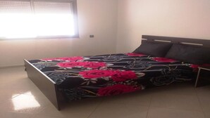 Um quarto com uma cama, uma janela e um chão de azulejos.