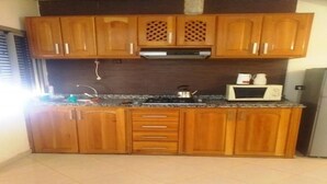 Cozinha com armários de madeira, micro-ondas e chaleira sobre o balcão.