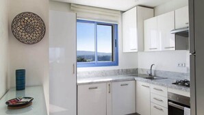 A modern kitchen with white cabinets, a gas stove, and a window with a view. - Splendid Sea View Apartment in Essaouira 5274 (Essaouira)
