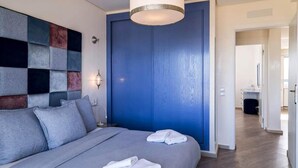 A modern bedroom with a large bed, a blue door, and a wall-mounted light fixture. - Splendid Sea View Apartment in Essaouira 5274 (Essaouira)
