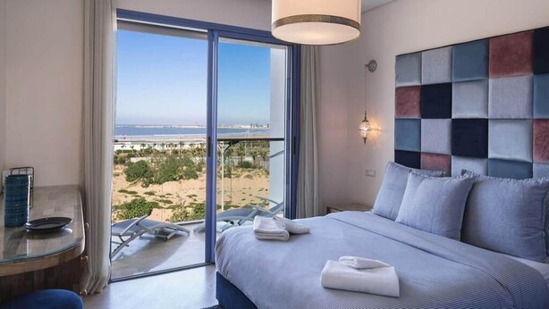 A hotel room with a large bed, a view of the beach, and a balcony. - Splendid Sea View Apartment in Essaouira 5274 (Essaouira)