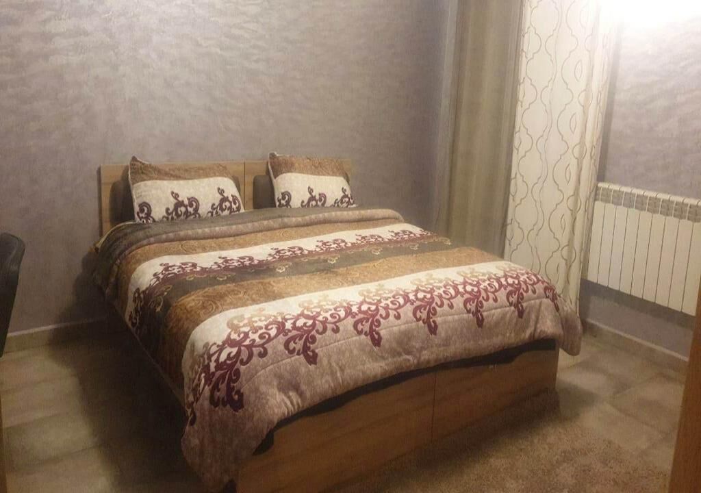 A bedroom with a wooden bed, patterned bedding, and a radiator.