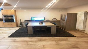 Una cocina moderna con una mesa de comedor, un televisor y electrodomésticos integrados.