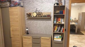 Una habitación con un armario de madera, un escritorio con cajones, una estantería con libros y una bicicleta, además de una biblioteca con diversos objetos.