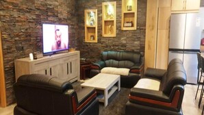 Una sala de estar moderna con una pared de piedra, sofás de cuero, una mesa de centro y un televisor.