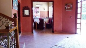 A spacious room with a wooden staircase, a dining area with chairs and a table, and a view of a kitchen through an open doorway. - Pleasant Villa with pool Route Targa Marrakech 5282 (Marrakech)