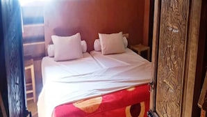A room with a bed, pillows, a wooden door, and a window. - DAR BOUMIDA 5289 Lalla Takerkoust (Lalla Takerkoust)