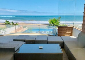 Un balcon avec vue sur l’océan, une piscine et un espace salon extérieur.