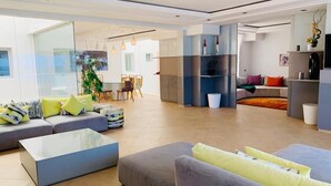 Ein modernes Wohnzimmer mit einer Sofagarnitur, einem Couchtisch und einem Essbereich mit Stühlen und Tisch.