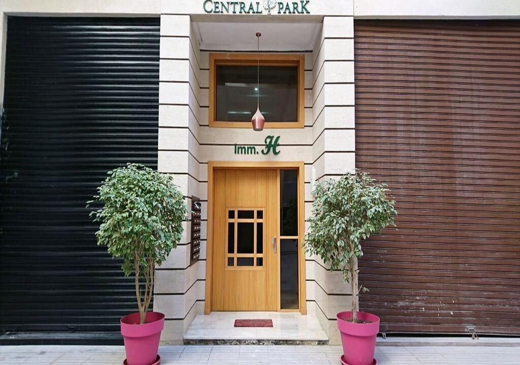 A building with a sign reading 'CENTRAL PARK' and 'Inn H' above a wooden door. There are two potted plants on either side of the entrance.