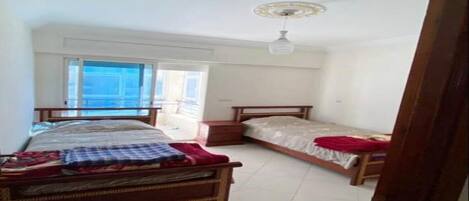 A bedroom with two beds, a window, a ceiling fan, and a tiled floor.