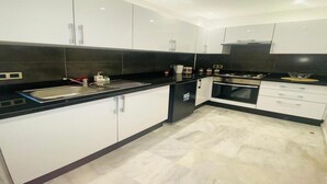 Una cocina moderna con armarios blancos, encimeras negras y salpicadero de azulejos.