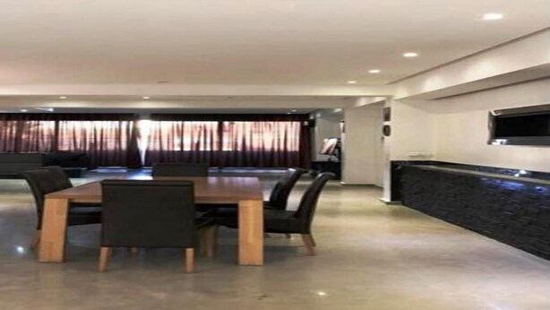 A modern dining area with a rectangular table and chairs, a dark accent wall, and a flat-screen TV mounted above the table. - High standing apartment in Guéliz 5345 (Marrakech)