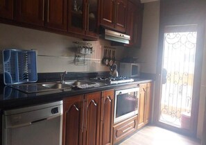 A kitchen with wooden cabinets, a stainless steel dishwasher, a stove, and a microwave.