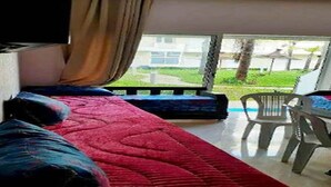Une pièce comprenant un lit, un canapé et donnant sur un jardin grâce à une fenêtre.
