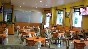 A restaurant with multiple tables and chairs, a projection screen, and a television on the wall. - Hotel Pal (Mexico City)