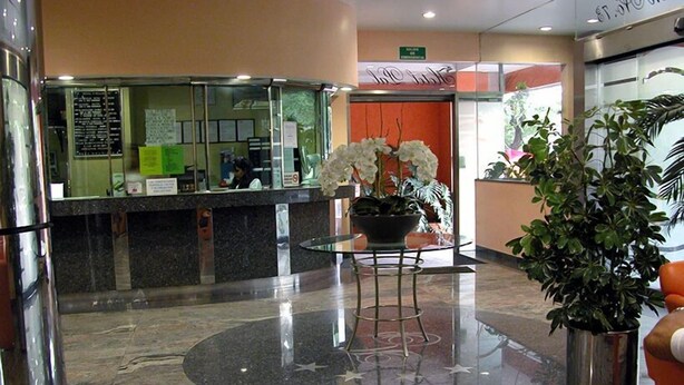 A hotel reception area with a marble floor, a reception desk, a potted plant, and a sign indicating the entrance to the hotel. - Hotel Pal (Mexico City)