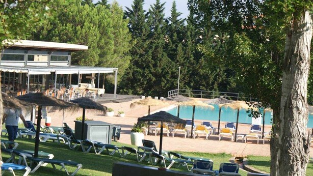 A poolside area with lounge chairs and umbrellas, a pool, and a building with a covered seating area. - Corbo apartment (Lagos)