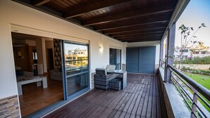 A covered outdoor area with a wooden deck, a seating area with a table and chairs, and a view of the surrounding buildings. - Corbo apartment (Lagos)