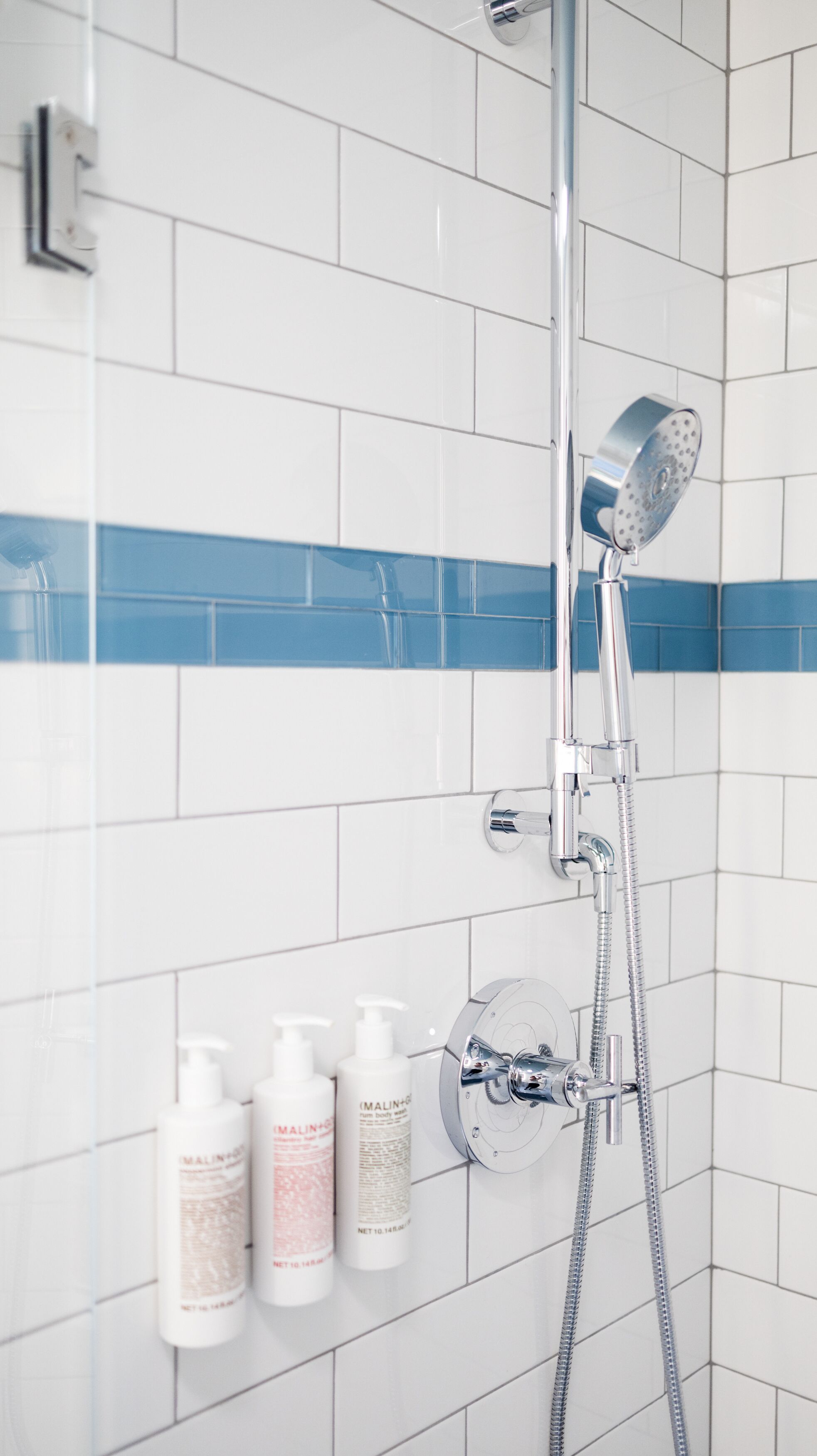 A shower with a chrome head, a flexible hose, and a wall-mounted control valve.