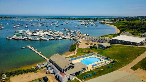 Vista aérea de un puerto deportivo con numerosas embarcaciones, una piscina y un edificio con muelle.