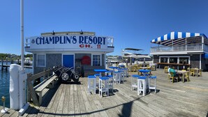 Un barco amarrado en Champlin's Resort, con un letrero, asientos al aire libre y un área cubierta con mesas y sillas.