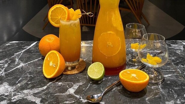 Un ambiente de restaurante con una mesa de mármol, bebidas y rodajas de naranja.