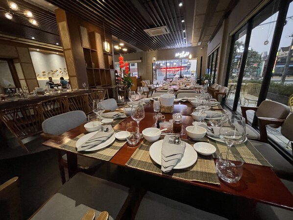 A restaurant with a long dining table set for a meal, surrounded by chairs.