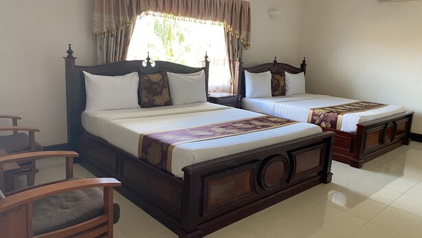 A hotel room with two wooden beds, a chair, and a window with curtains. - Asian Koh Kong Hotel (Khemarak Phoumin)