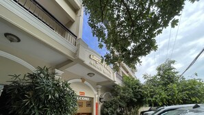 Entrada de hotel con un letrero que dice "Asian Hotel" y un cartel de bienvenida.